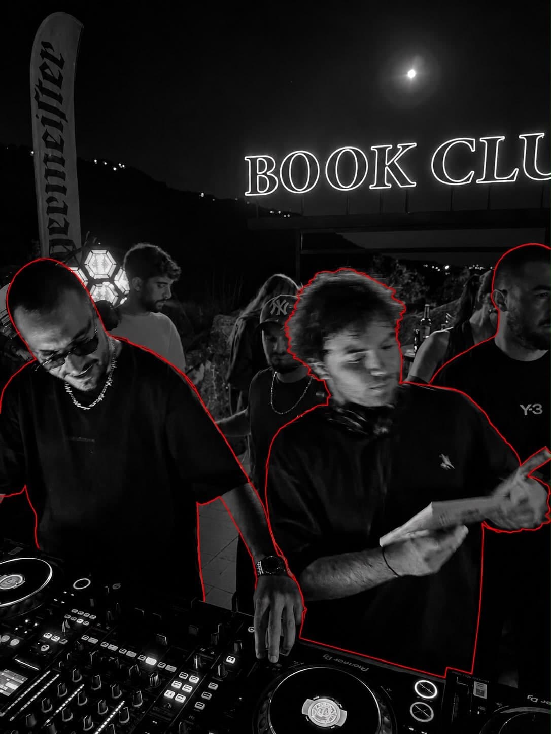 Two people at the DJ decks under a 'Book Club' neon sign with the moon visible overhead, shot in black and white with a red color-pop outline