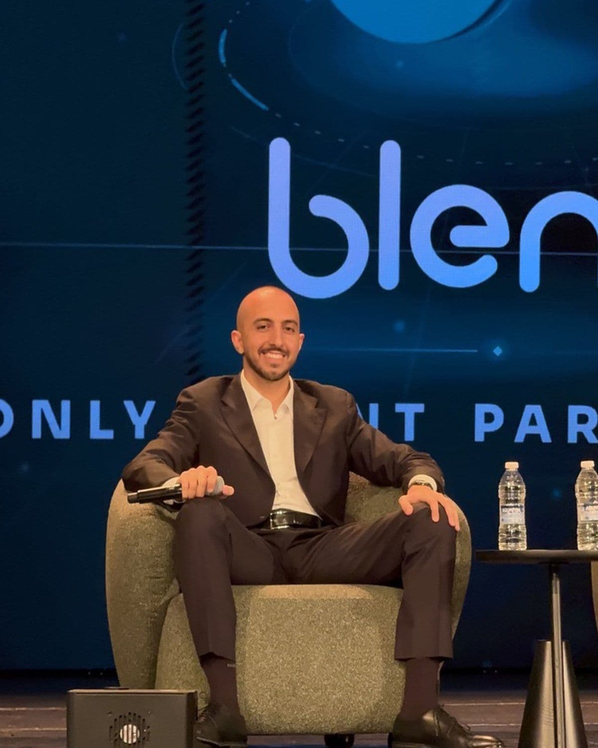 A Blend co-founder seated on stage in front of the Blend screen during the panel
