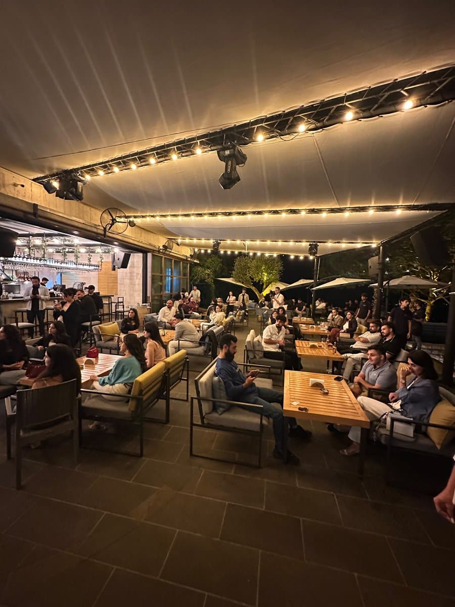 A wide view of Network With Jean's rooftop venue filled with guests networking at lounge seating under string lights