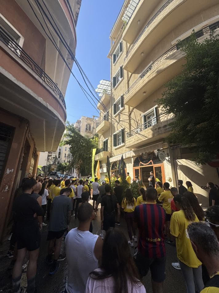 A large crowd in yellow Sabah El Kheir Run t-shirts filling a narrow Beirut street before the run