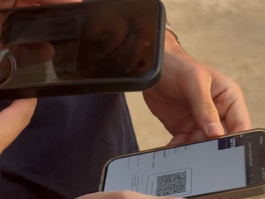 A door staff member scans a guest's QR ticket on their phone at the Taht El Amar entrance