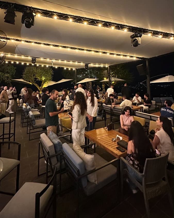 Guests networking under string lights on the rooftop at a Network With Jean event in the Chouf